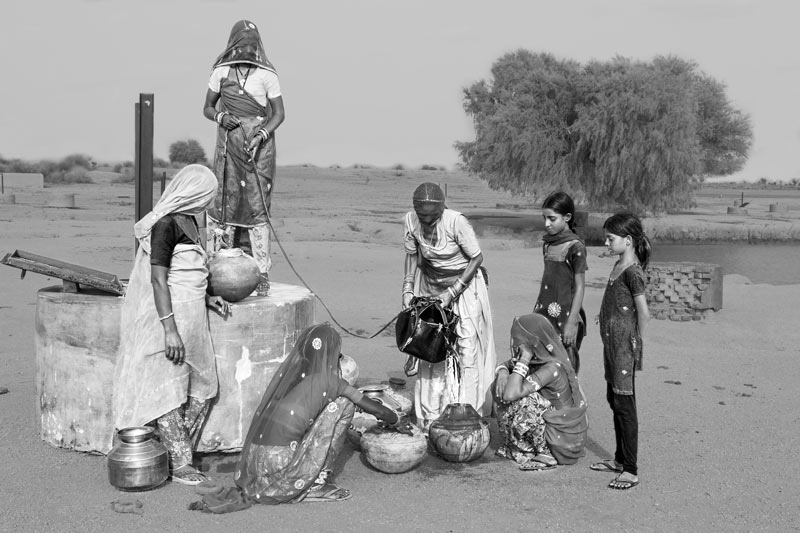 Pitchers being filled with water drawn from a 'kuin'(shallow well) - village Binjharwali, Bikaner district, Rajasthan